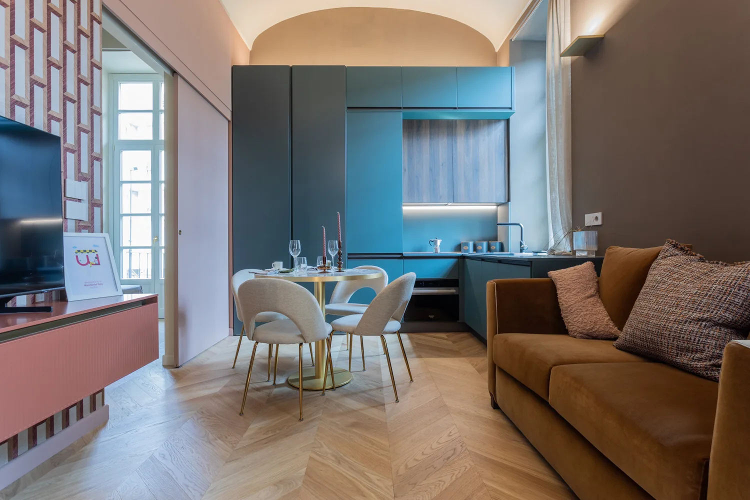 A modern living and dining area features a table, seating, and a brown sofa.