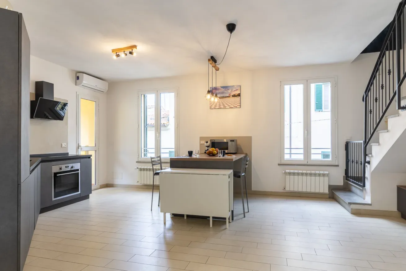 Cocina y comedor de concepto abierto con una mesa junto a las ventanas.