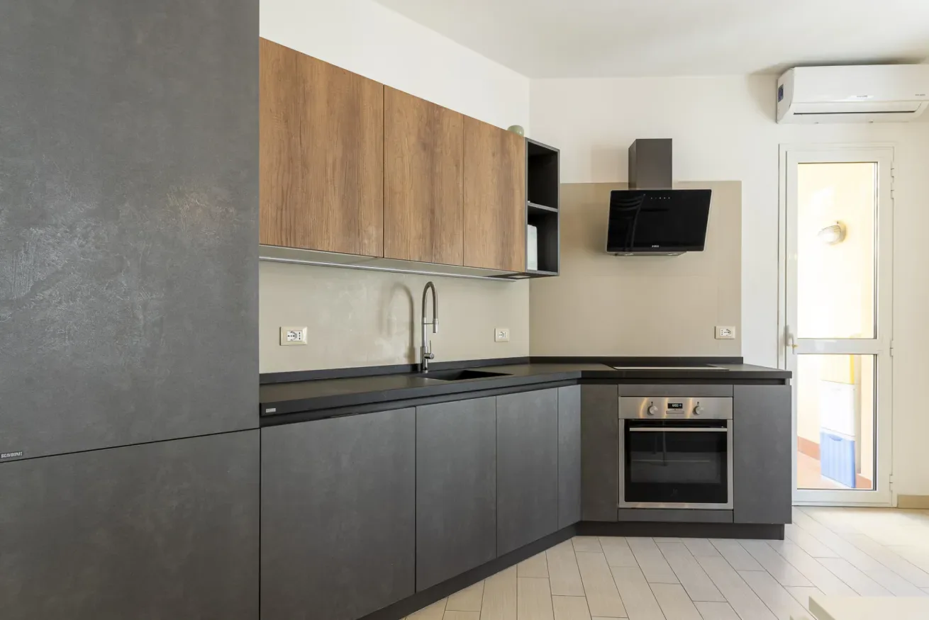 Una cocina moderna con armarios superiores de tono madera y armarios inferiores oscuros.