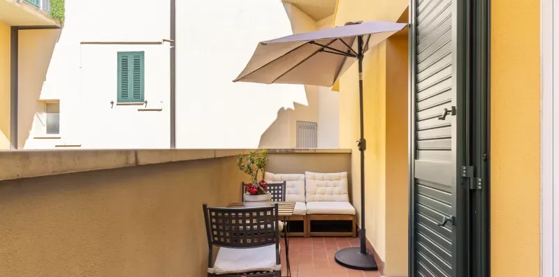 A sunlit terrace with outdoor seating and a large umbrella.