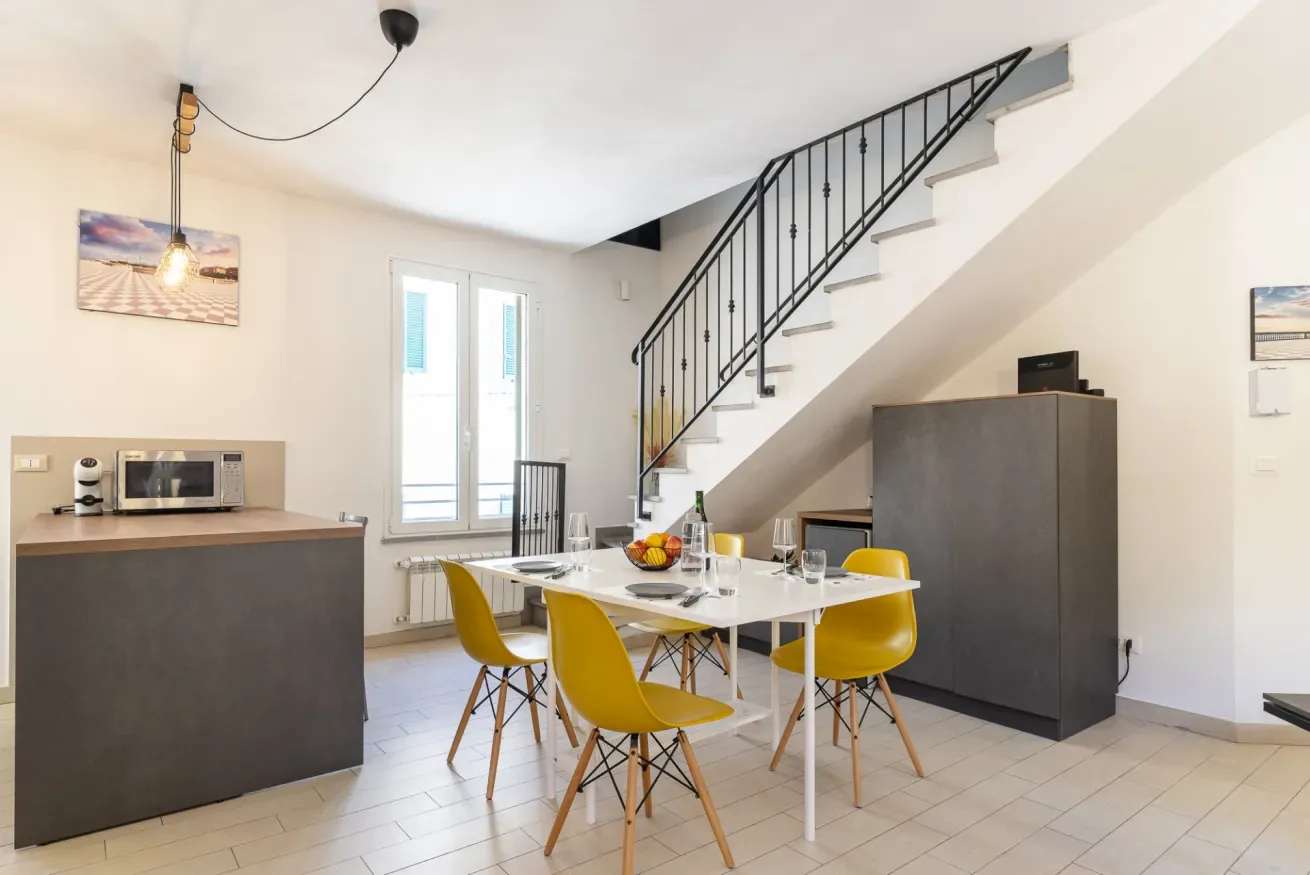Un comedor con una mesa y asientos amarillos está junto a una escalera.