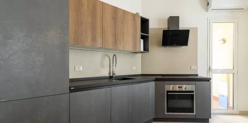 Una cocina moderna con muebles oscuros, una encimera y un horno.