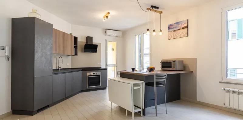 Una cocina moderna con gabinetes oscuros, una isla central y lámparas colgantes.