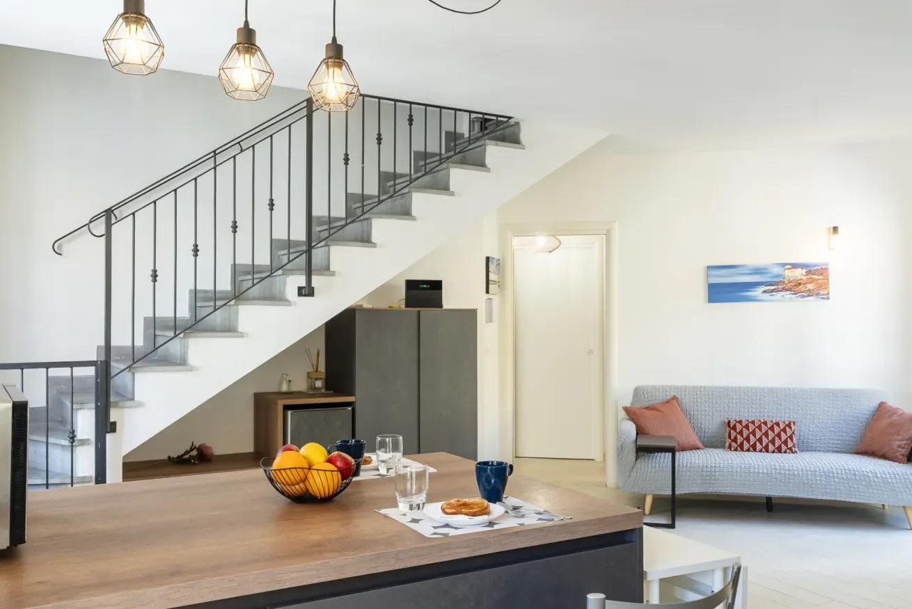 Una sala luminosa con una escalera, una mesa de comedor y asientos.
