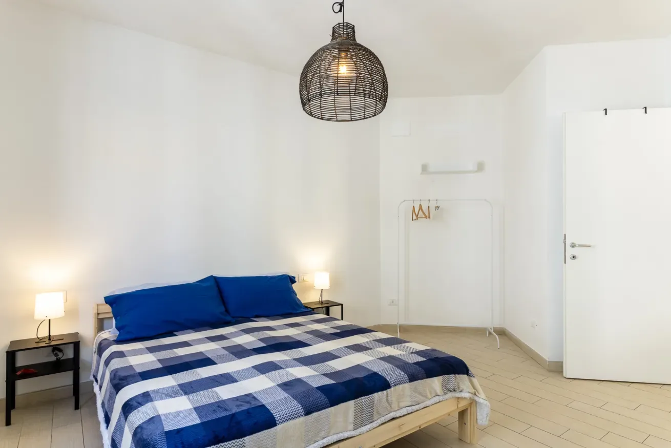 Un dormitorio luminoso con una cama vestida con ropa de cuadros azules y blancos.