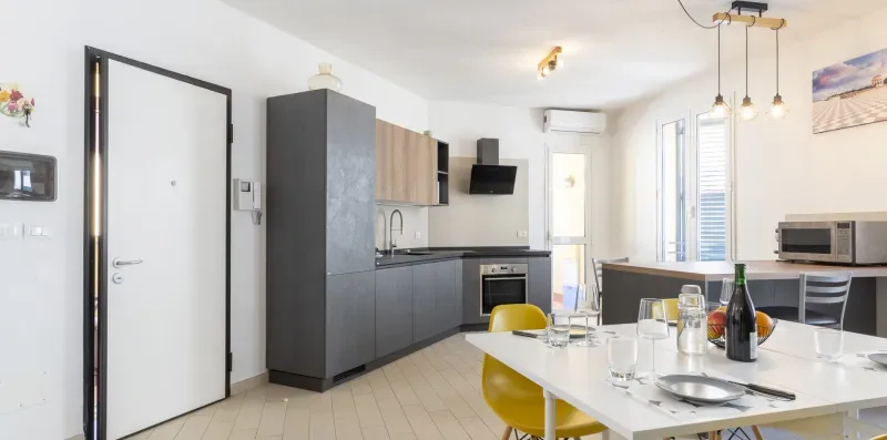 Una cocina luminosa con gabinetes grises y una mesa blanca.