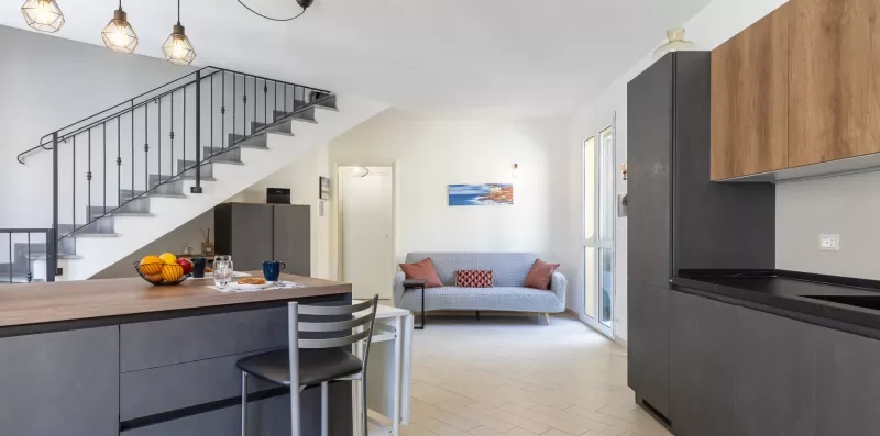 An open-plan kitchen and living area with a staircase and seating.