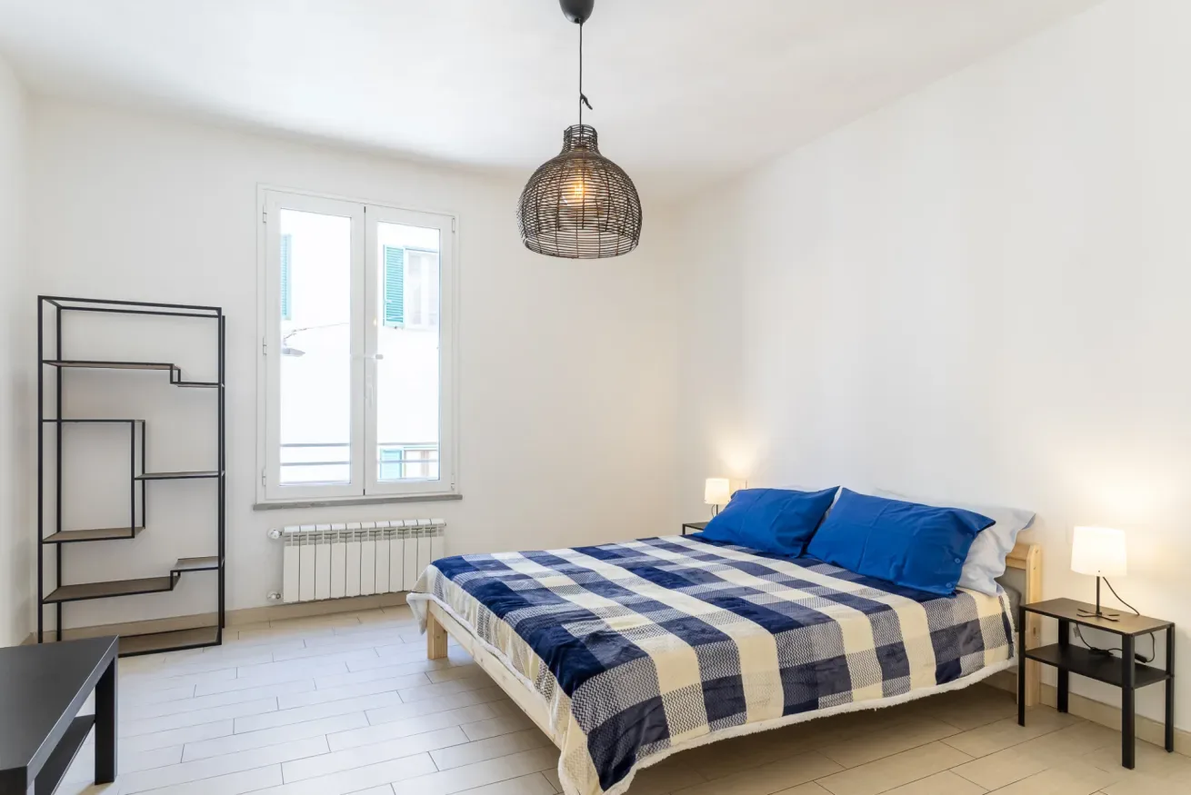 Un dormitorio luminoso con una cama cubierta con ropa de cuadros azules y blancos.