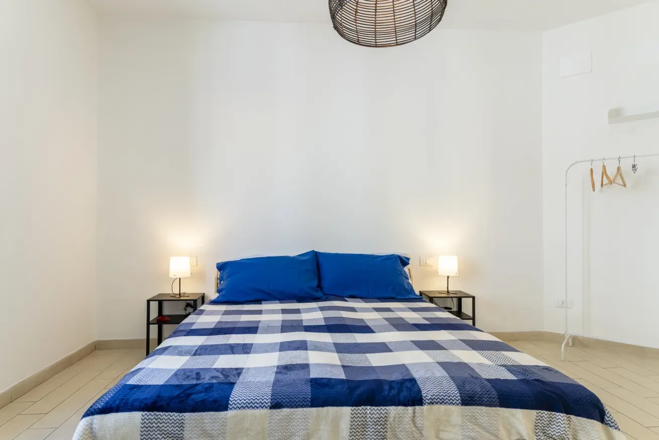 Dormitorio con una cama vestida de cuadros azules y blancos y lámparas de noche.