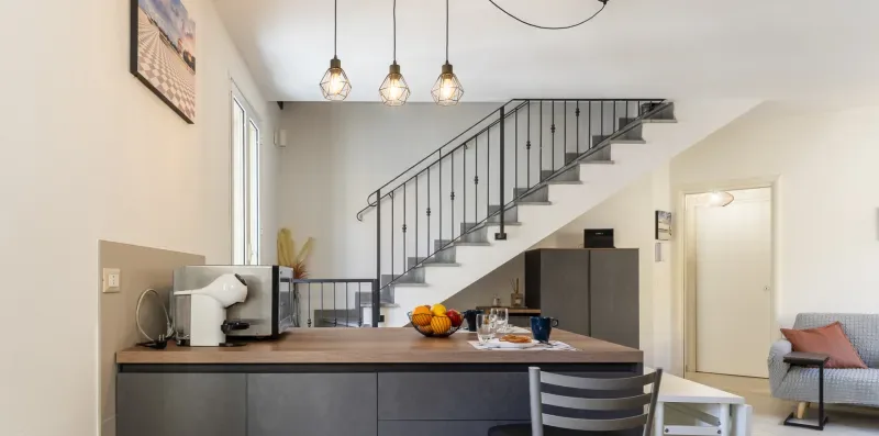 Una cocina abierta y un comedor quedan bajo una escalera.