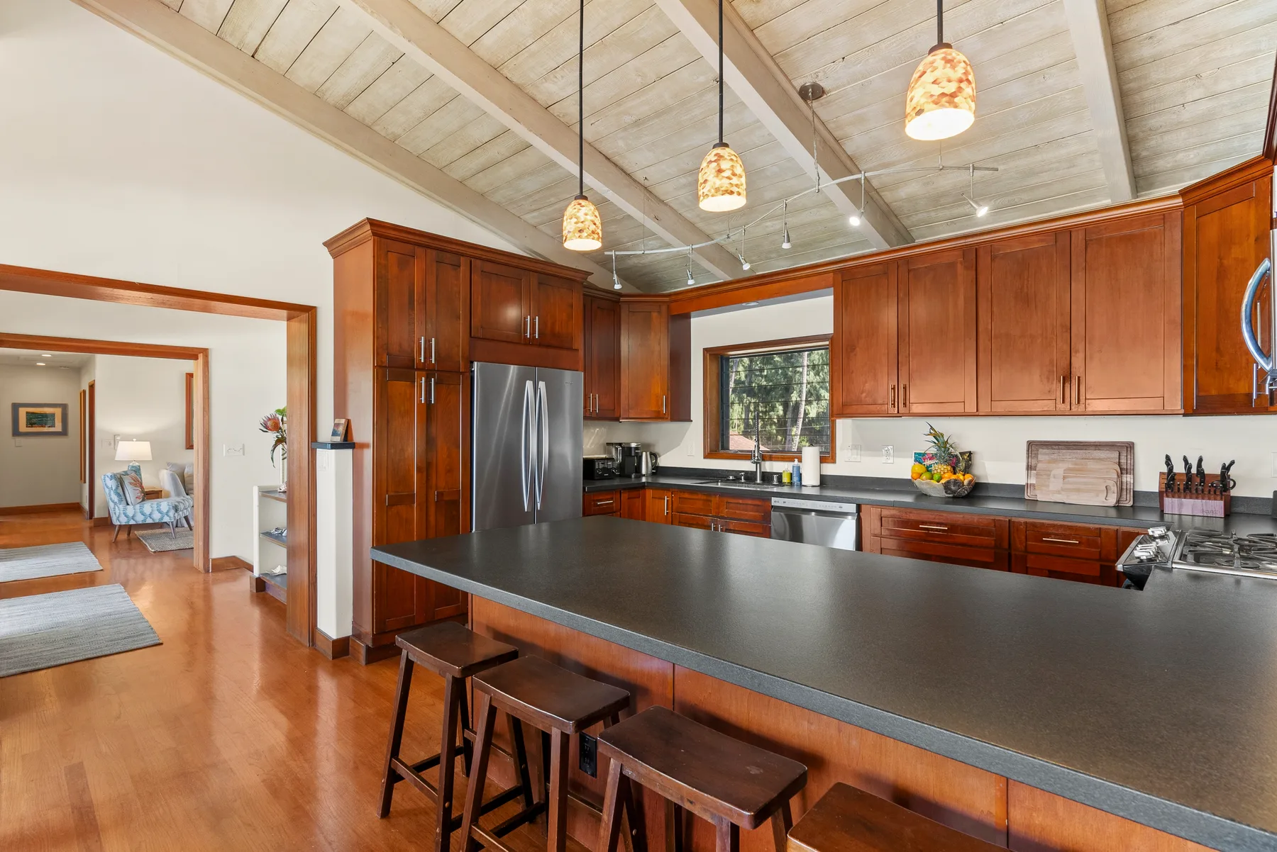 Una cocina amplia con gabinetes de madera oscura, una isla grande y lámparas colgantes.