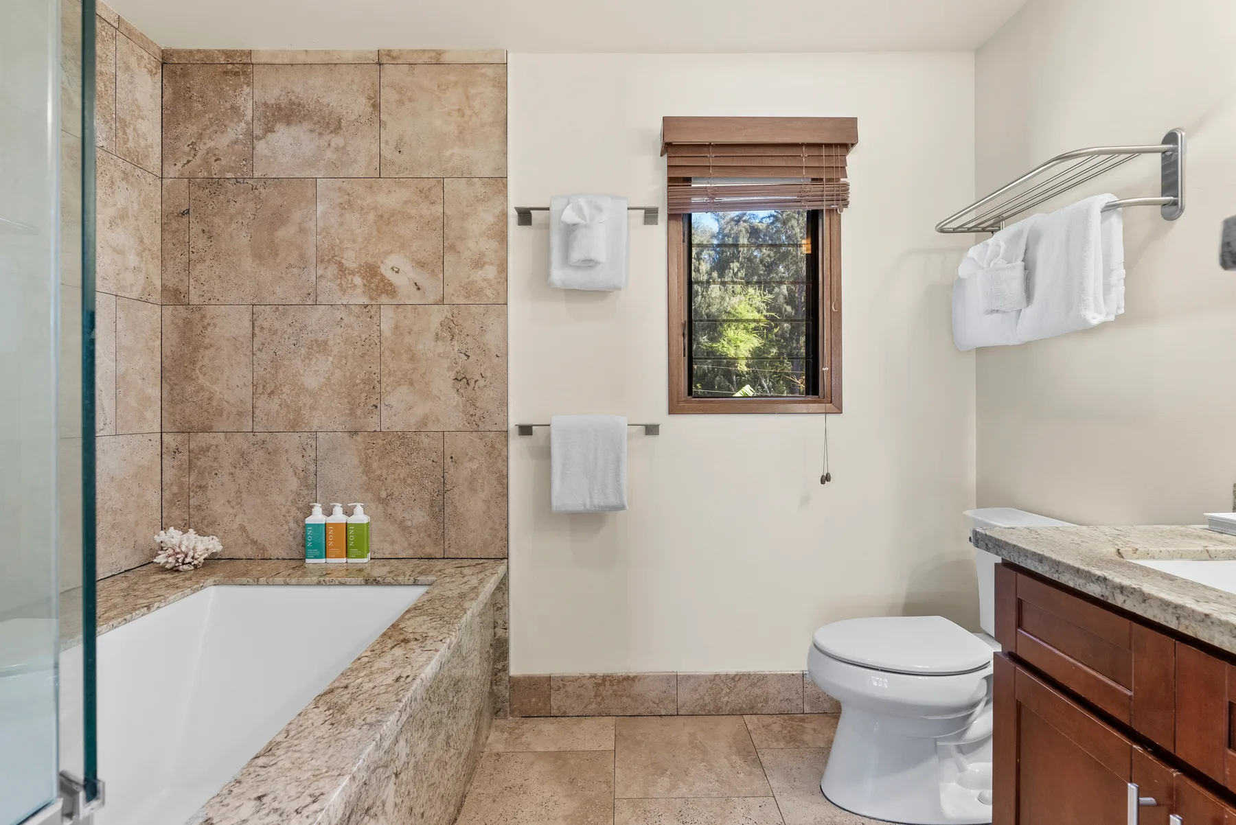 Un baño con bañera, inodoro y tocador de madera.