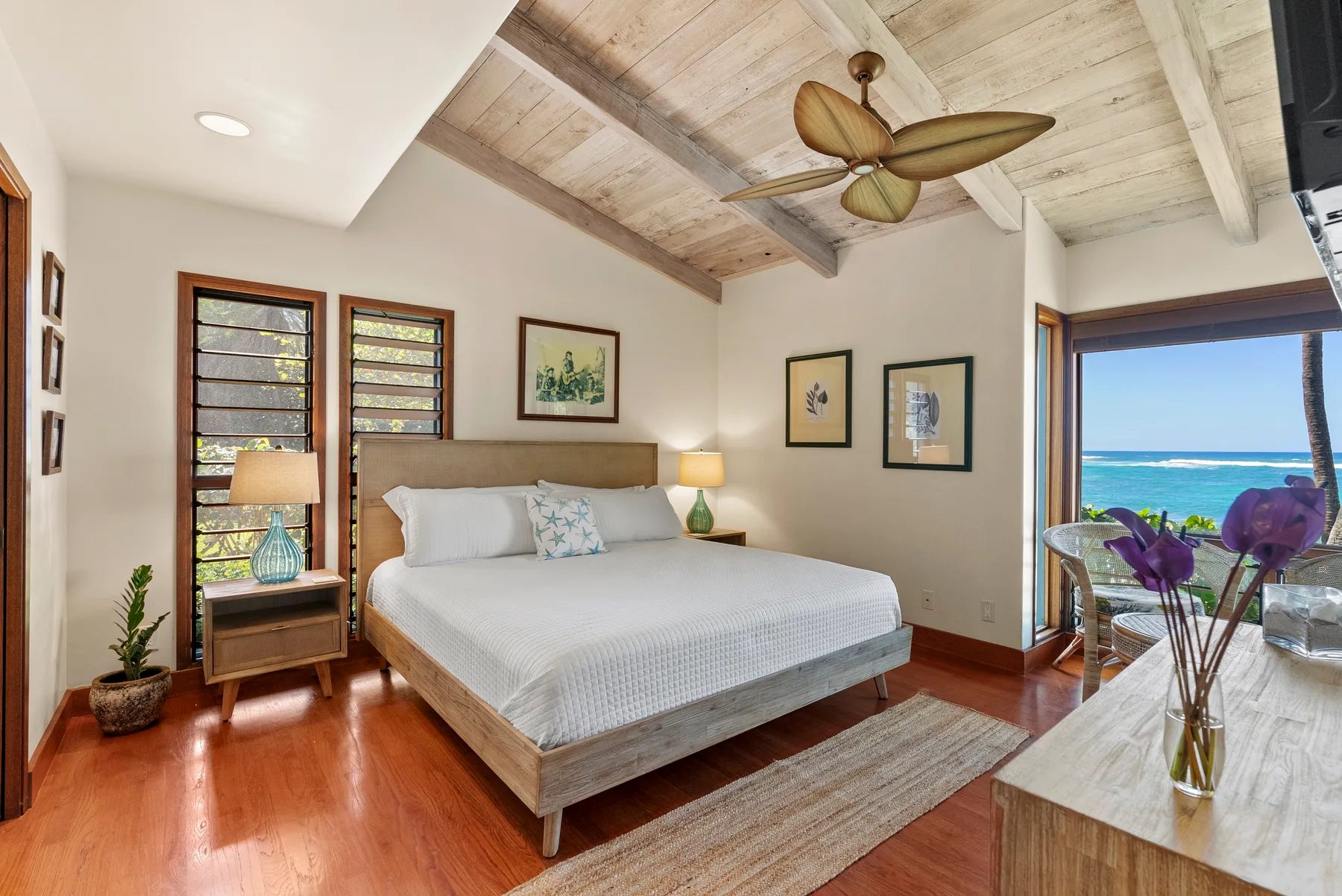 Un dormitorio luminoso con una cama y vistas al mar por las puertas abiertas.