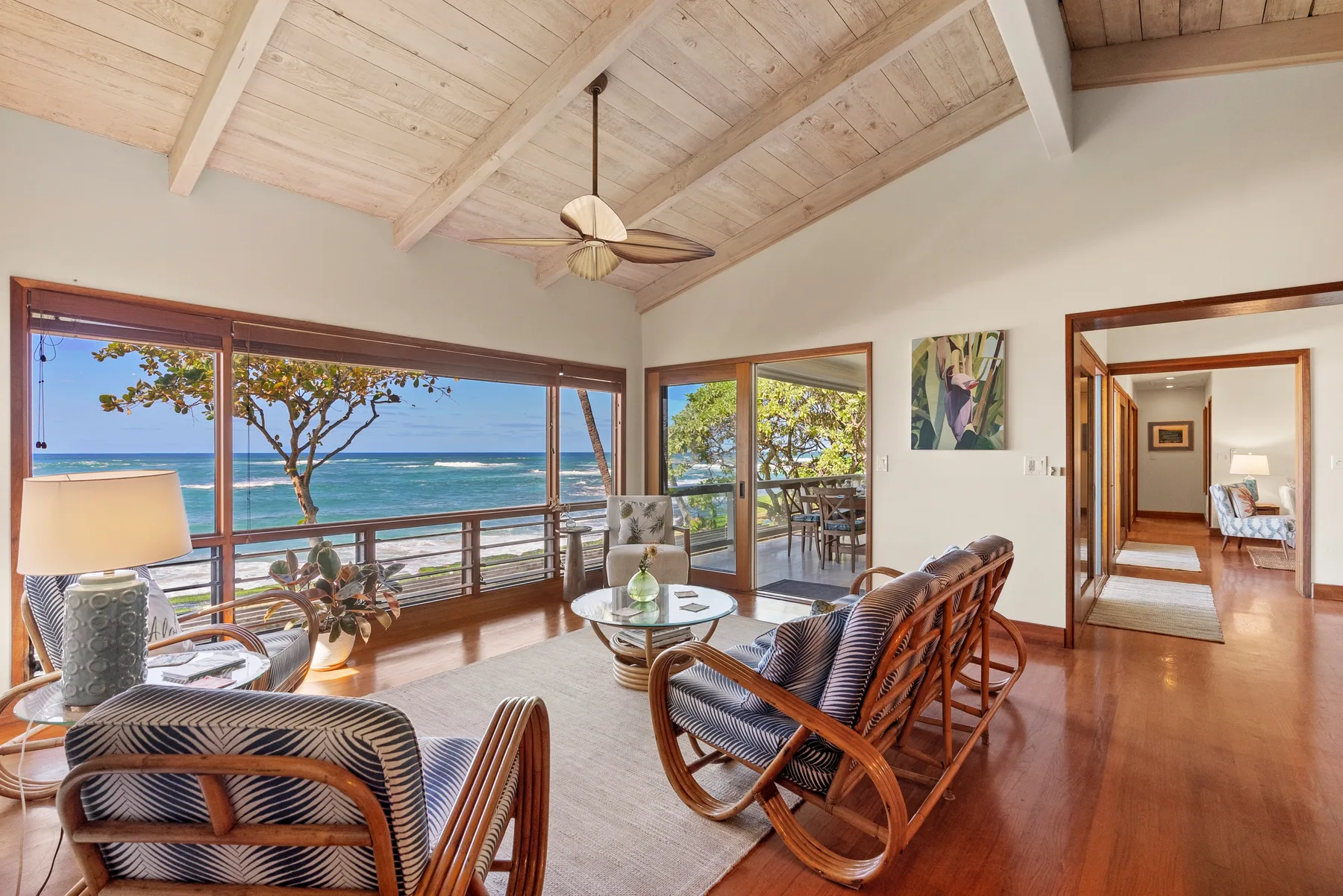 A bright living room with seating and large windows overlooking the ocean.