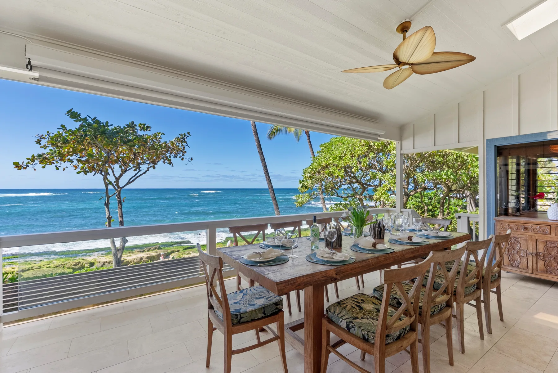 Una zona de comedor abierta da al mar, con una mesa preparada para comer.