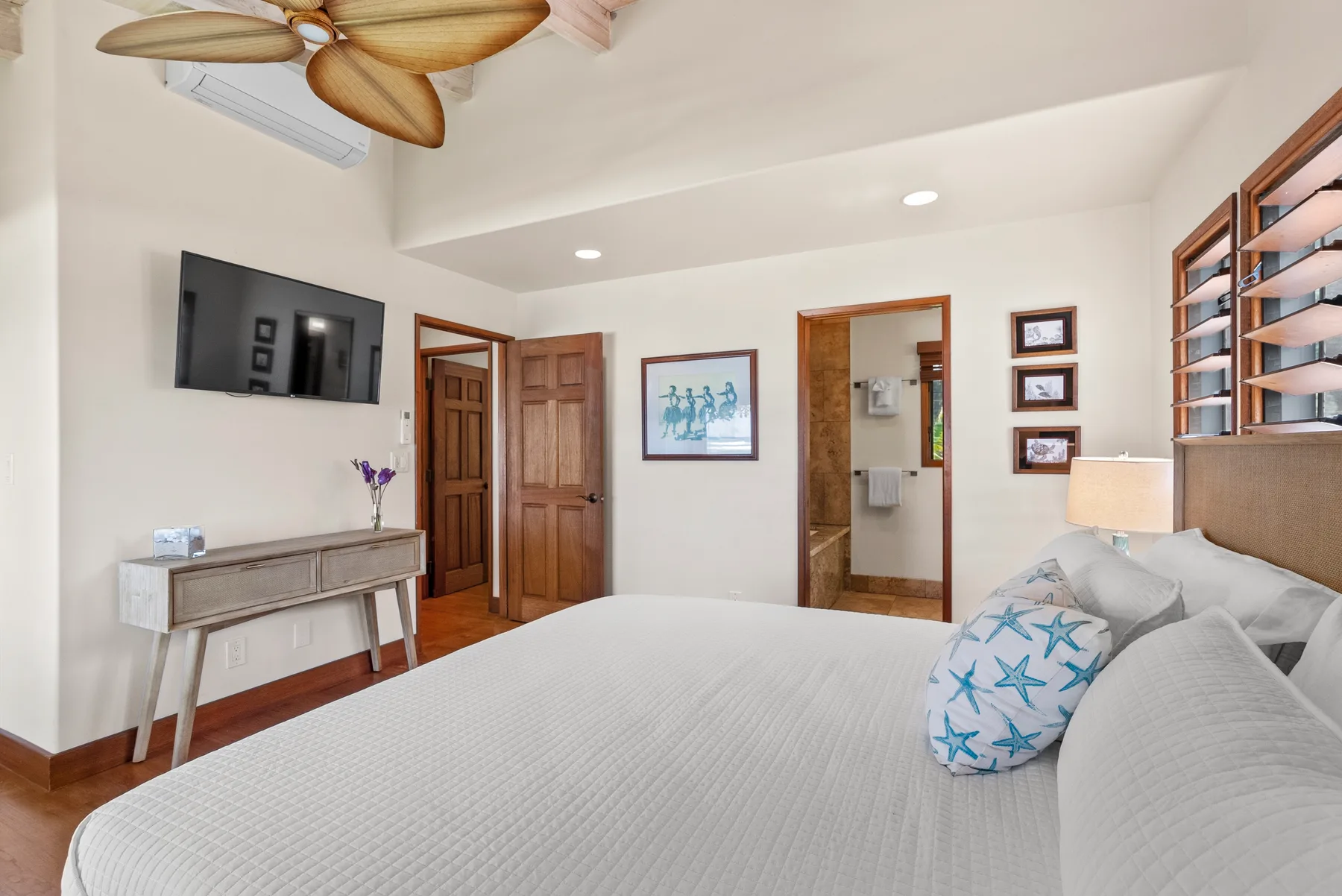 Un dormitorio con una cama grande, un televisor en la pared y varias puertas de madera.