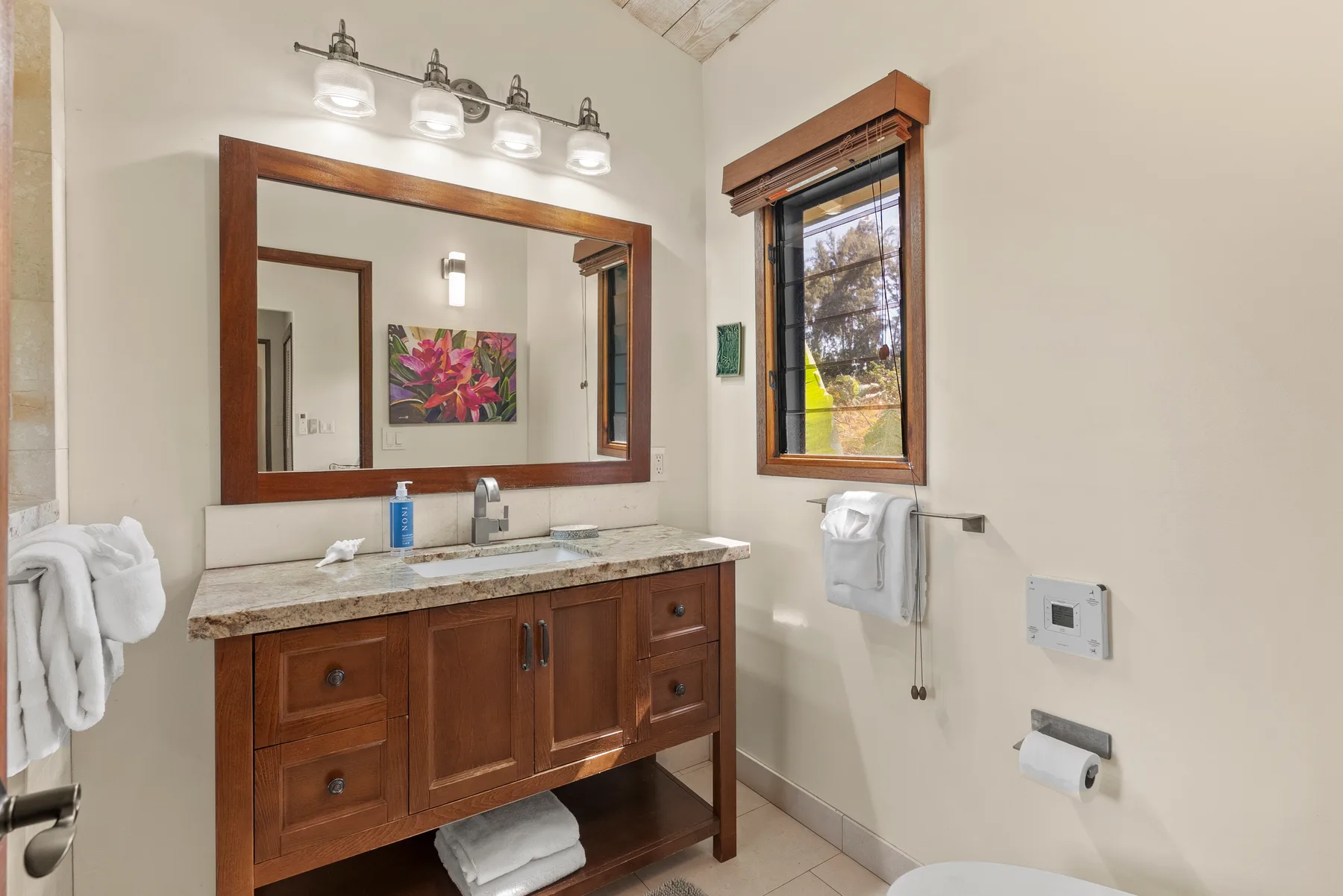 Un mueble de baño con un espejo grande está junto a una ventana.