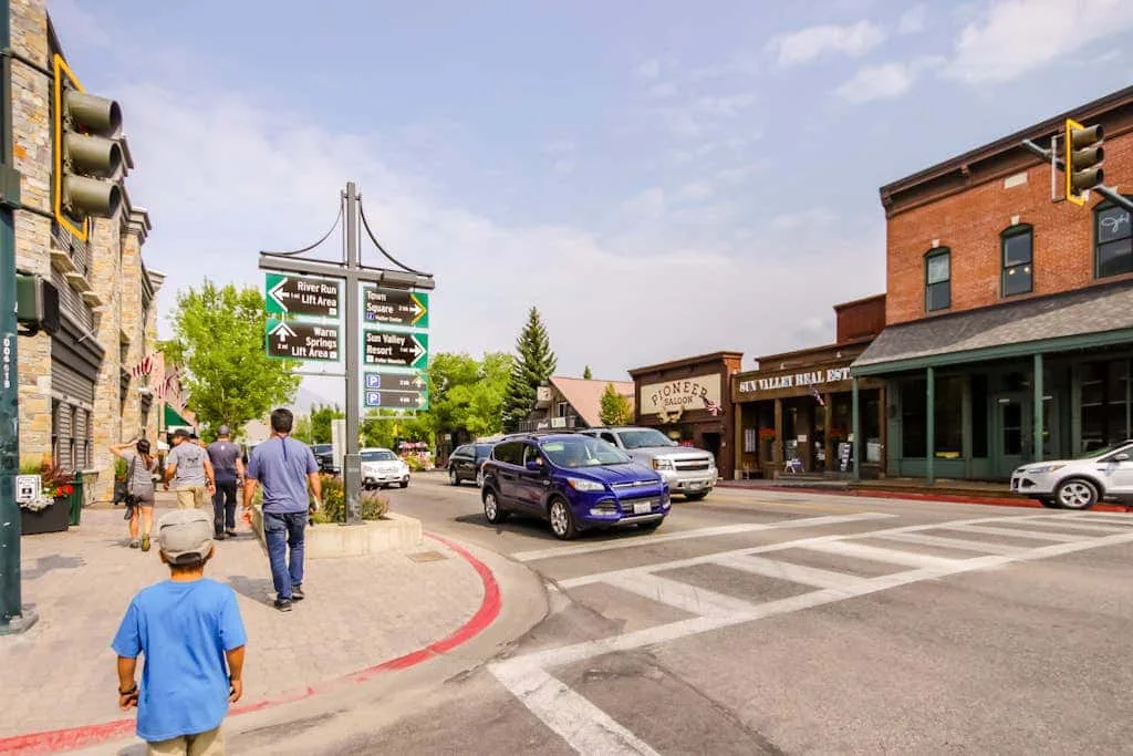 A downtown street intersection with storefronts, traffic signs, and pedestrians.