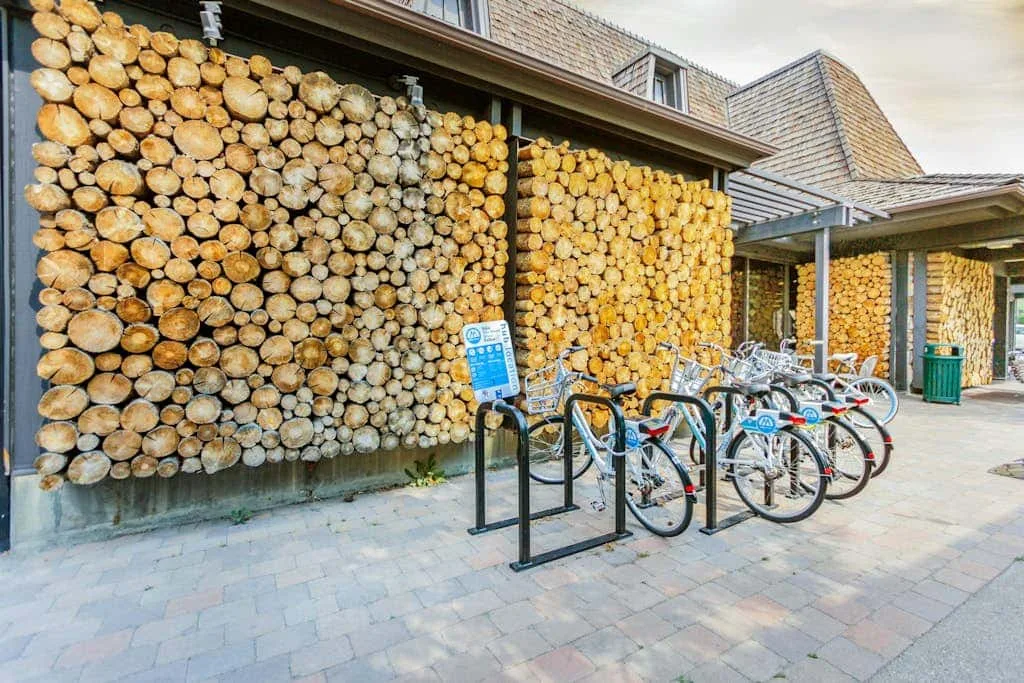 A bicycle parking area sits in front of a wall stacked with firewood.