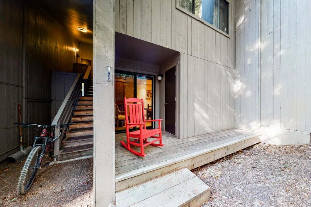 A wooden porch with a red rocking chair beside the entrance and an outdoor staircase.