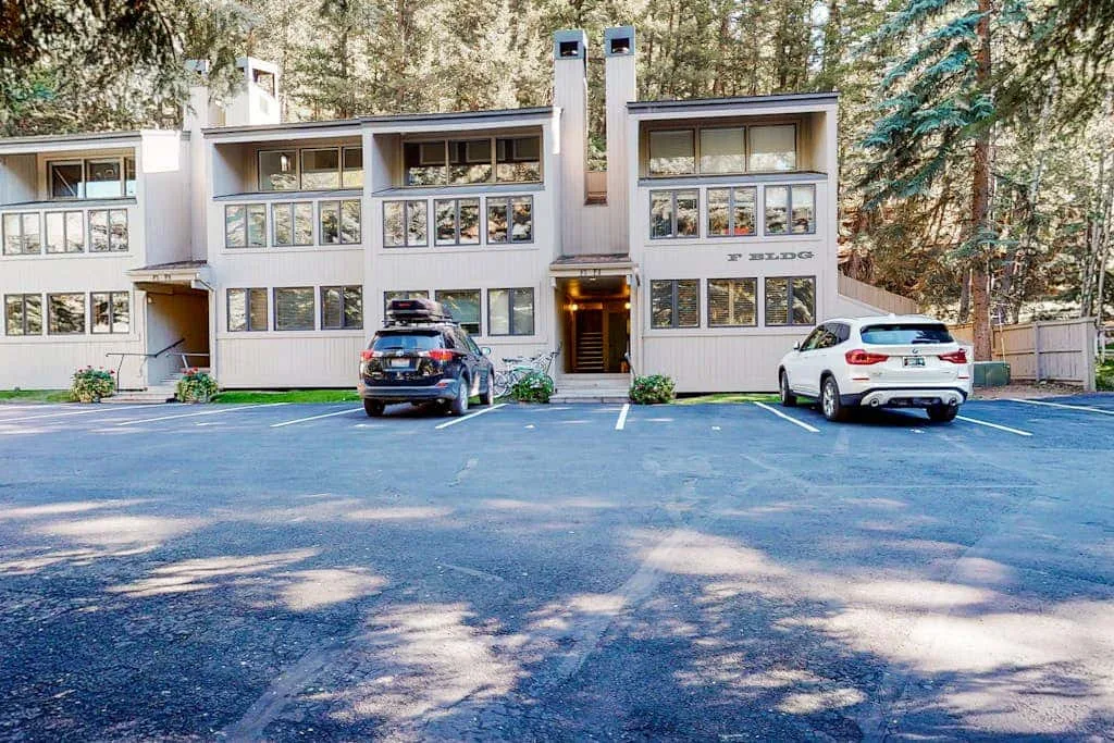 A multi-story building with rows of windows faces a paved parking area.