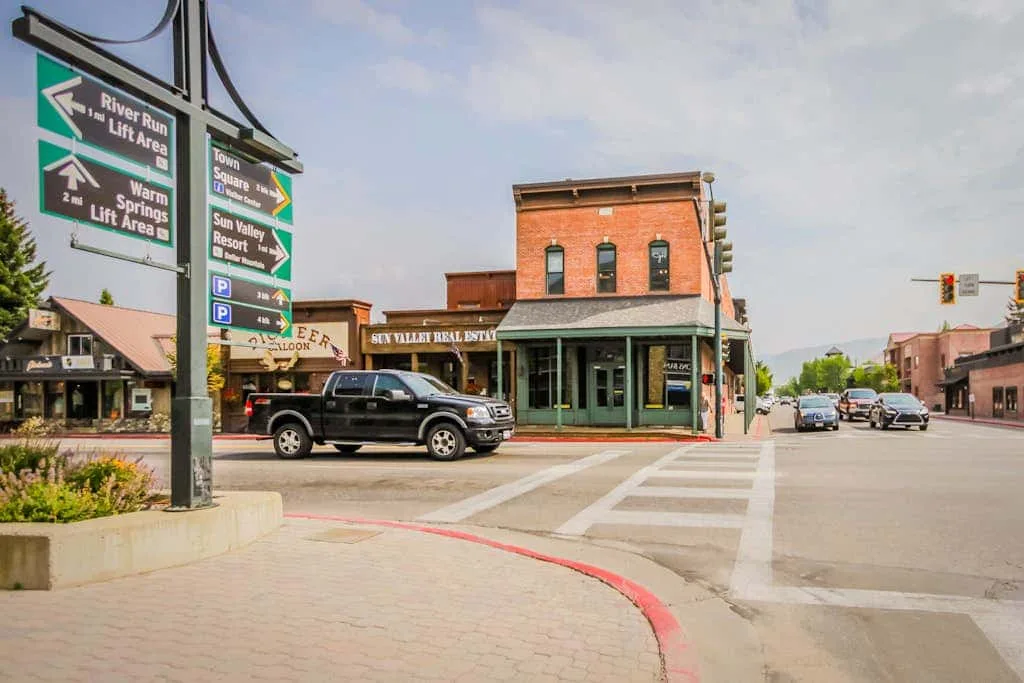 A downtown street intersection with a brick storefront and directional signs.