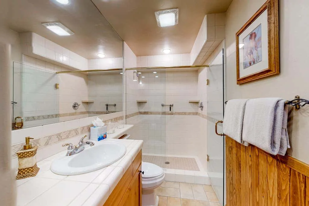 A tiled bathroom with a sink, toilet, and glass shower.