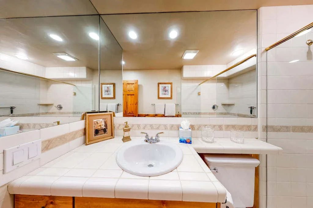 A tiled bathroom with a wide vanity, sink, and large wall mirror.
