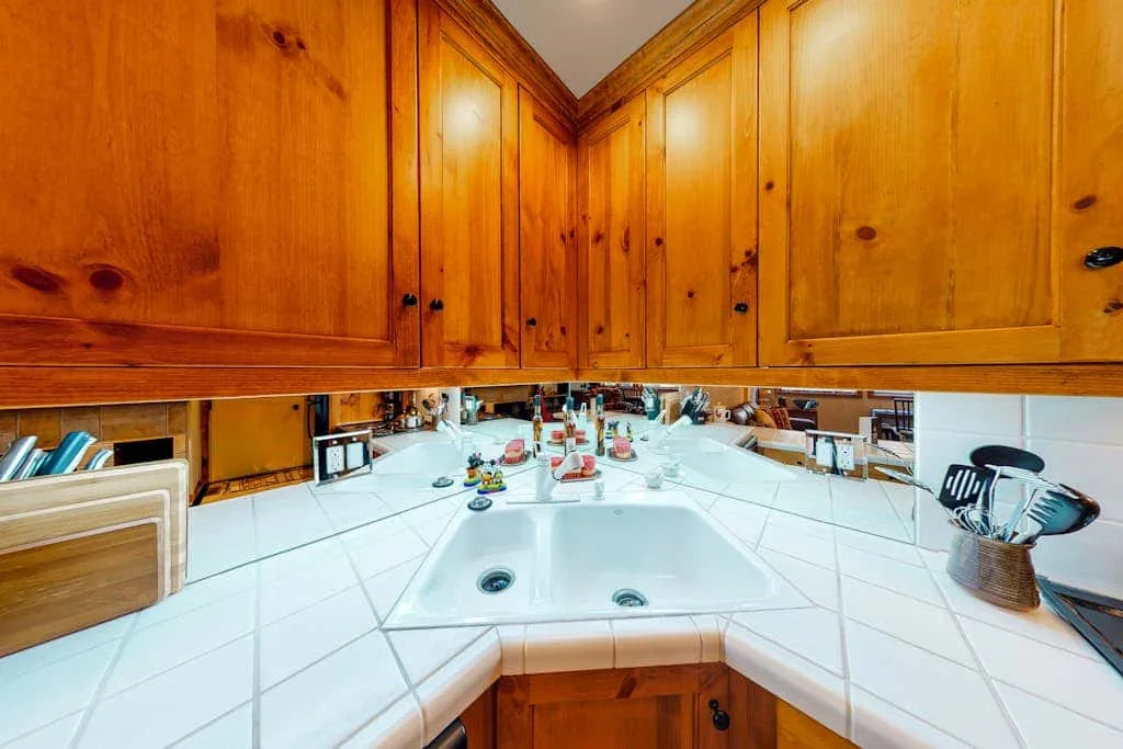 A kitchen counter with a double-basin sink sits beneath wooden cabinets.