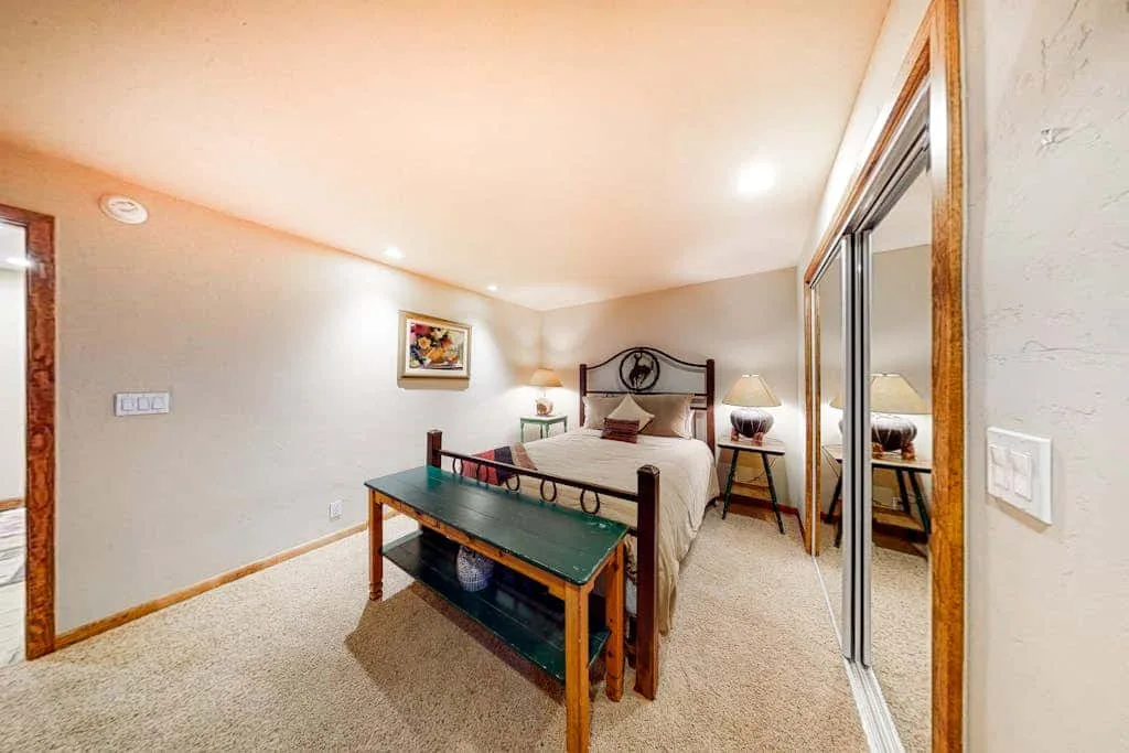 A bedroom with a bed, bedside tables, and mirrored closet doors.