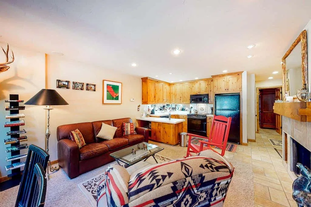 A living room with a brown sofa and an open kitchen.