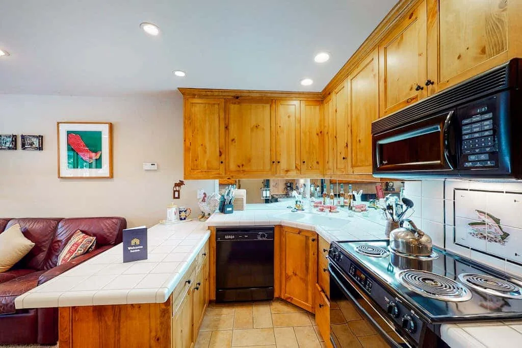 Kitchen with wooden cabinets, a tiled counter, and cooking appliances.