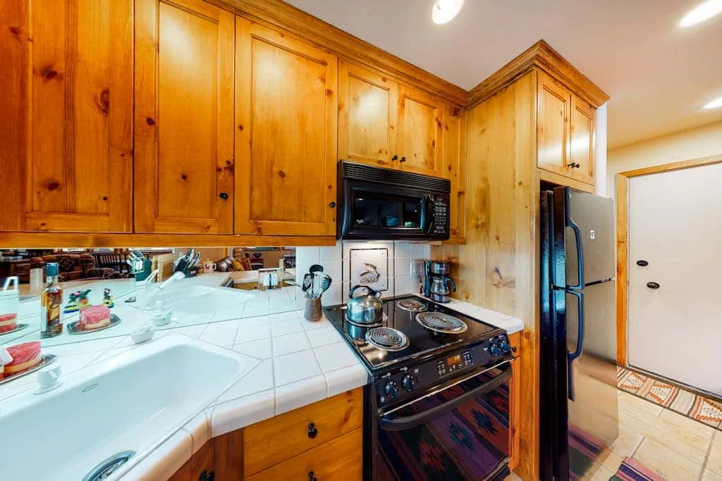 A kitchen with wooden cabinets, a tiled countertop, and a stove.