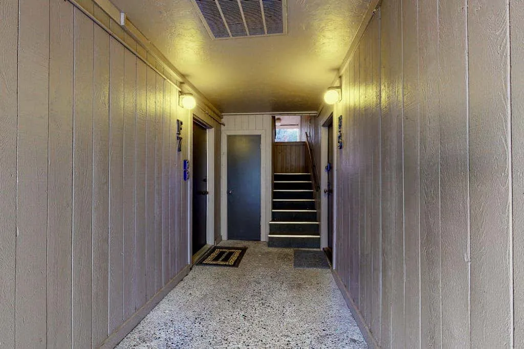 A narrow indoor hallway leads to a short staircase.