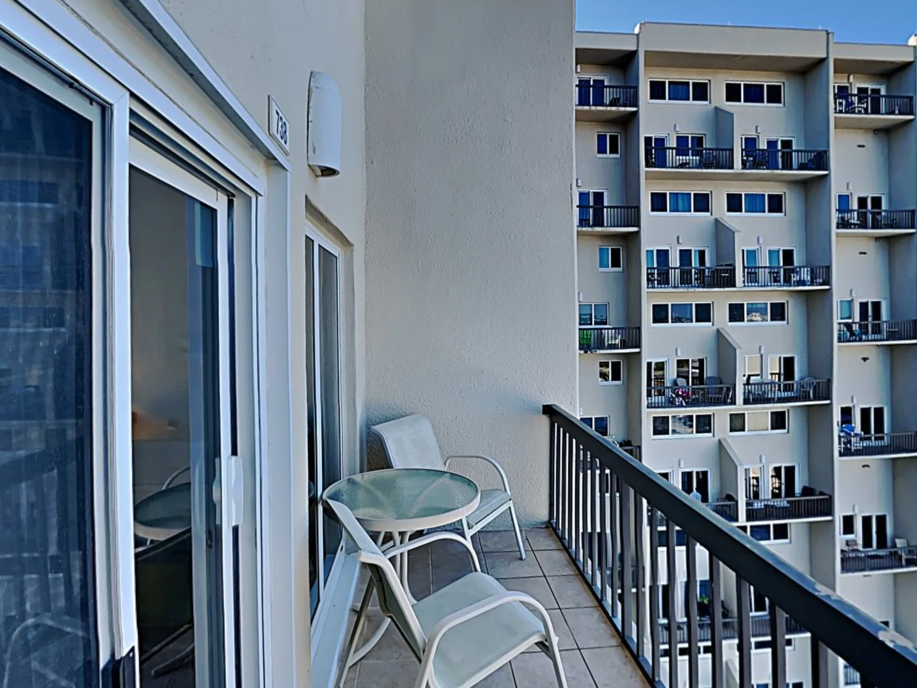 A balcony with seating overlooks a neighboring apartment building.