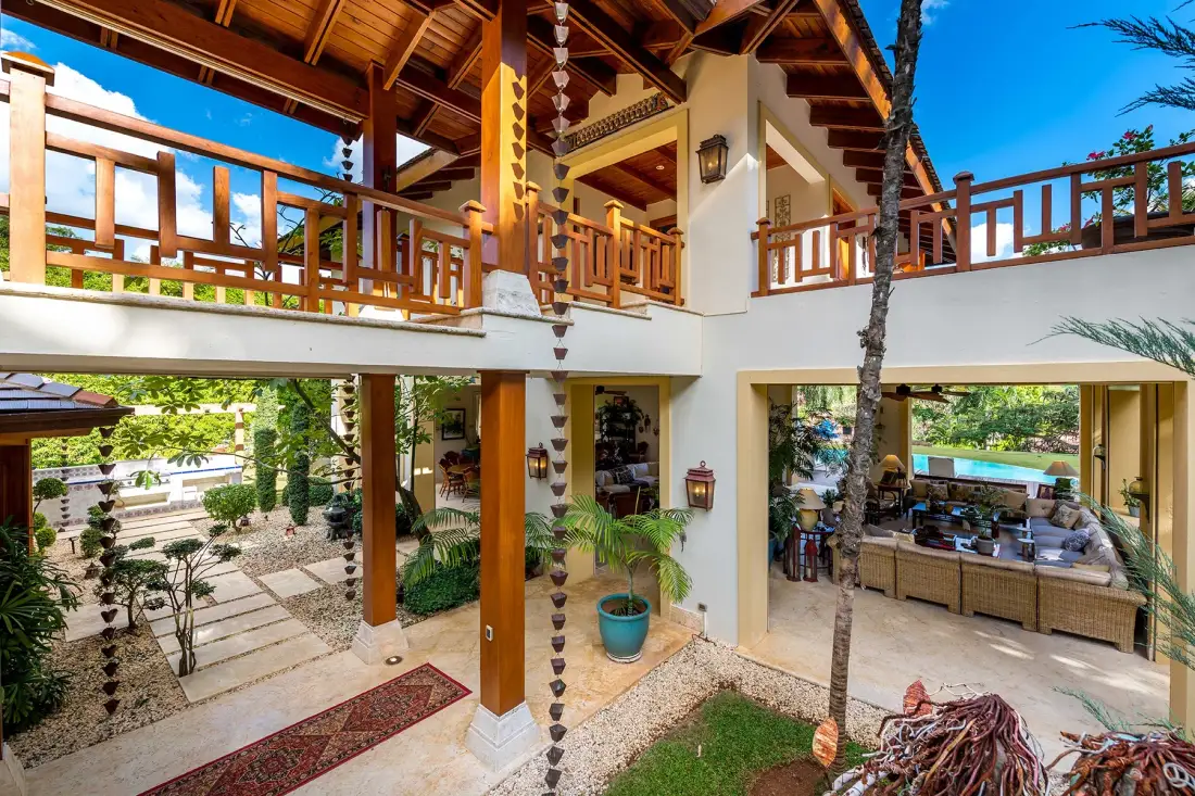 A two-level open-air courtyard with wooden balconies and a dining area.