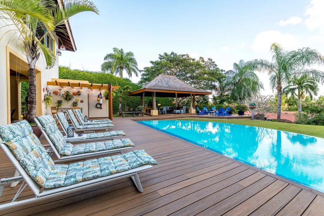 An outdoor swimming pool beside a wooden deck with lounge seating.