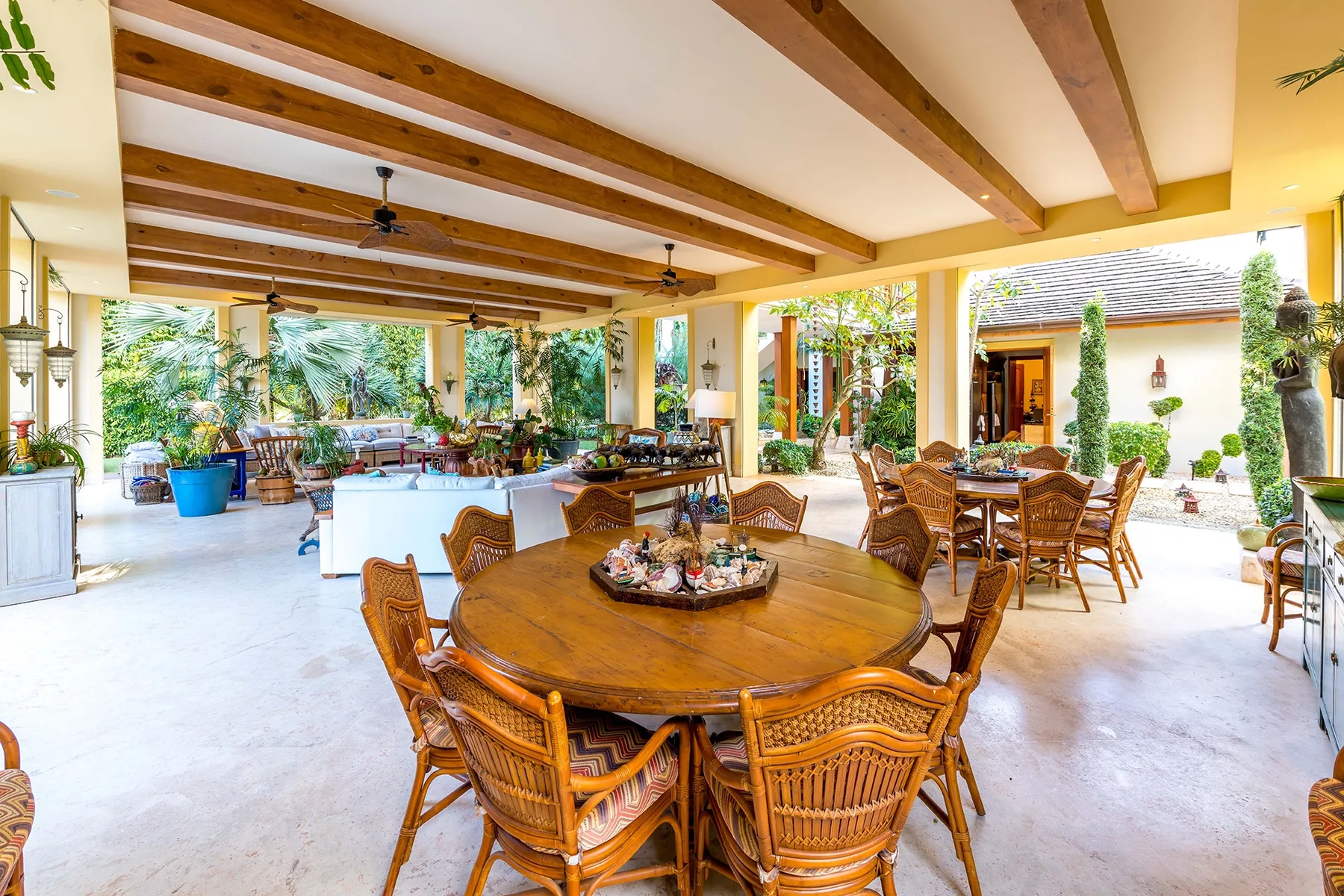 A covered outdoor dining area with wooden tables and woven seating.