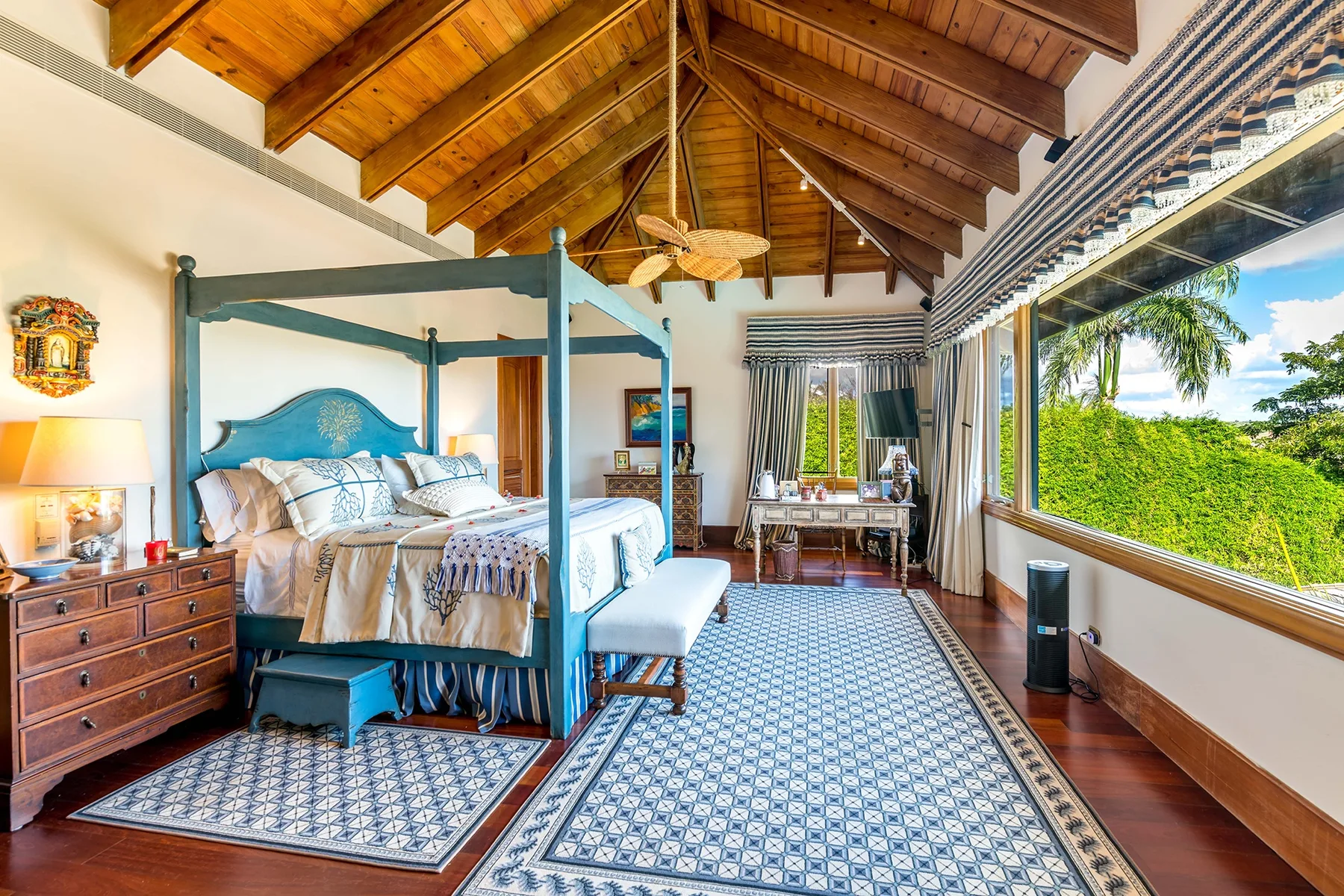 A bedroom with a canopy bed, patterned floor tiles, and a high wooden ceiling.