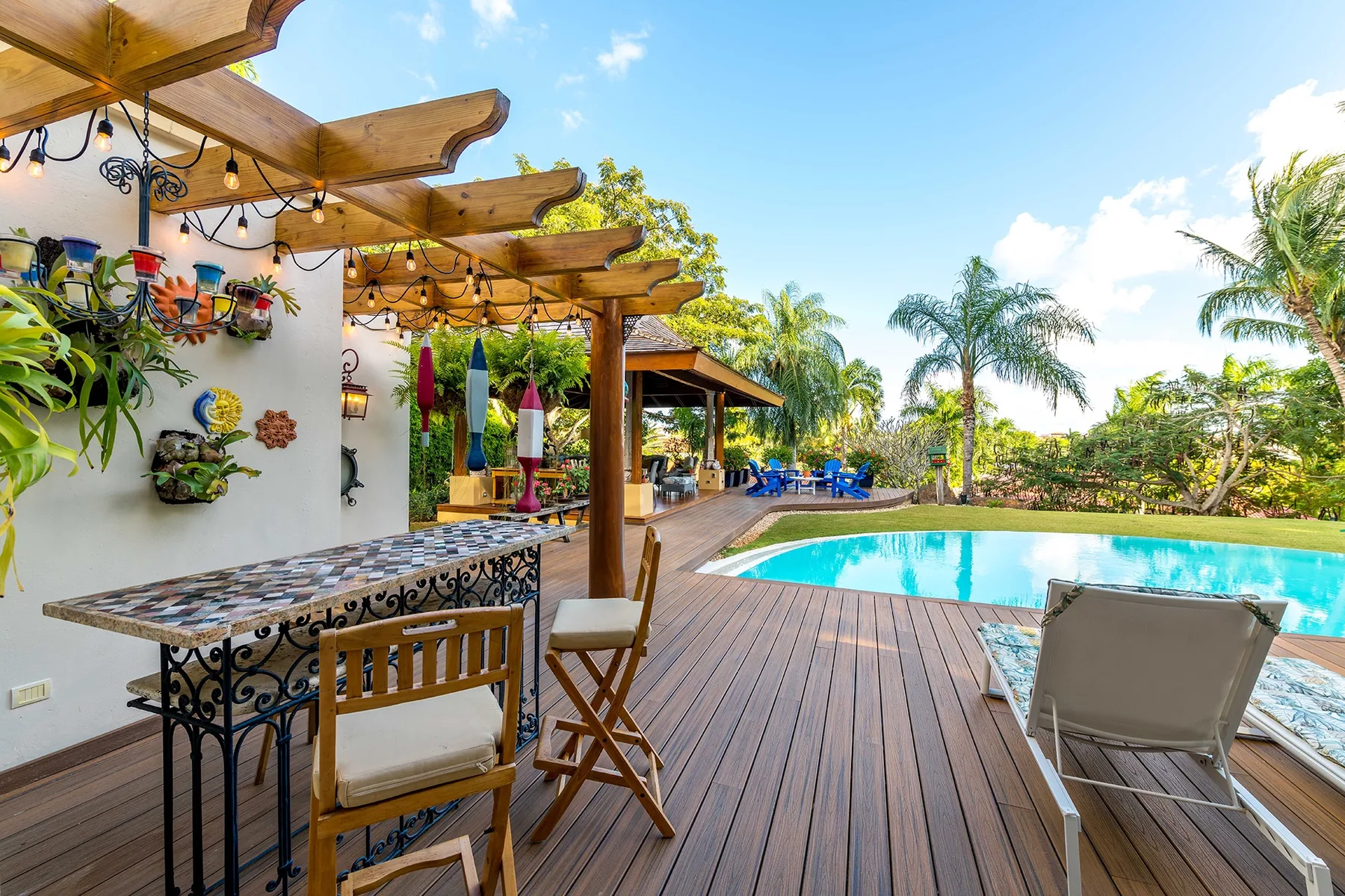 An outdoor patio with a wooden deck, dining table, and swimming pool.