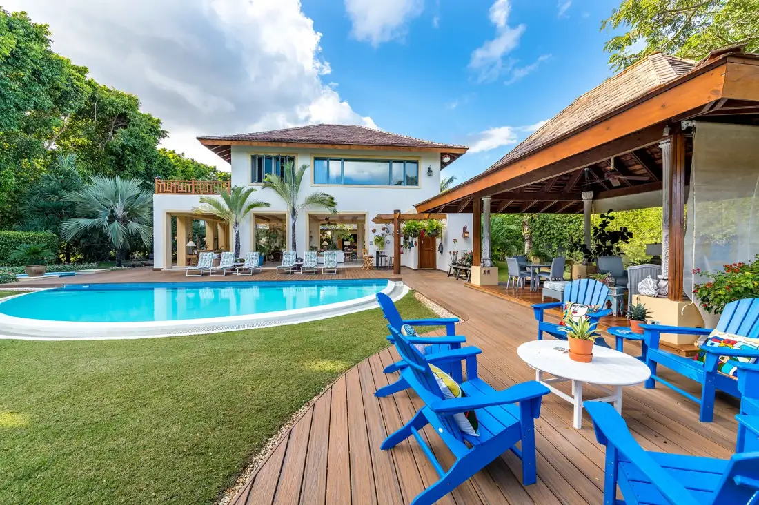 A modern house opens onto a swimming pool and a deck with outdoor seating.