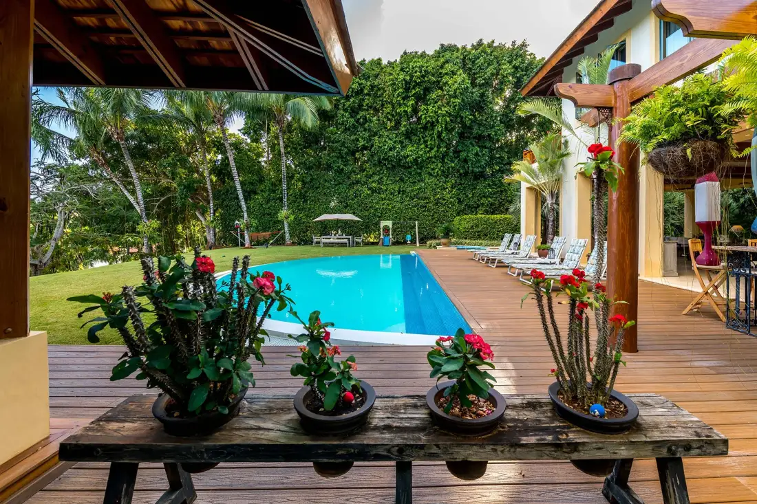 An outdoor swimming pool beside a wooden deck and lush garden.