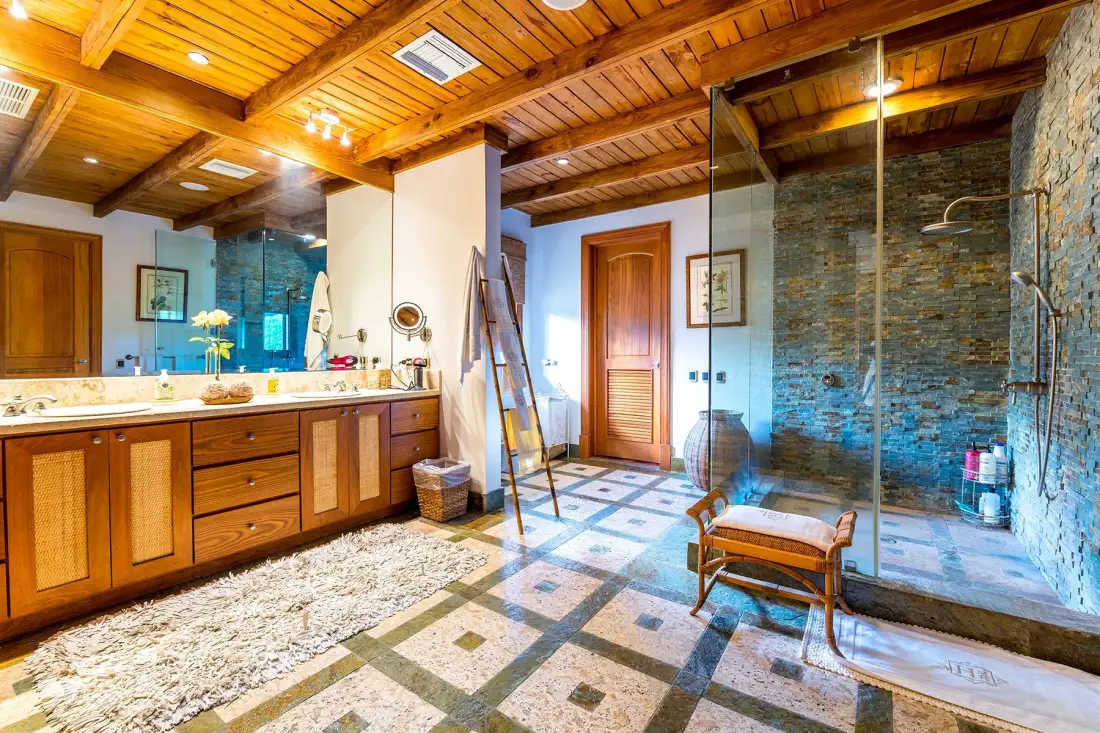 A bathroom with a long wooden vanity and a glass-enclosed shower area.