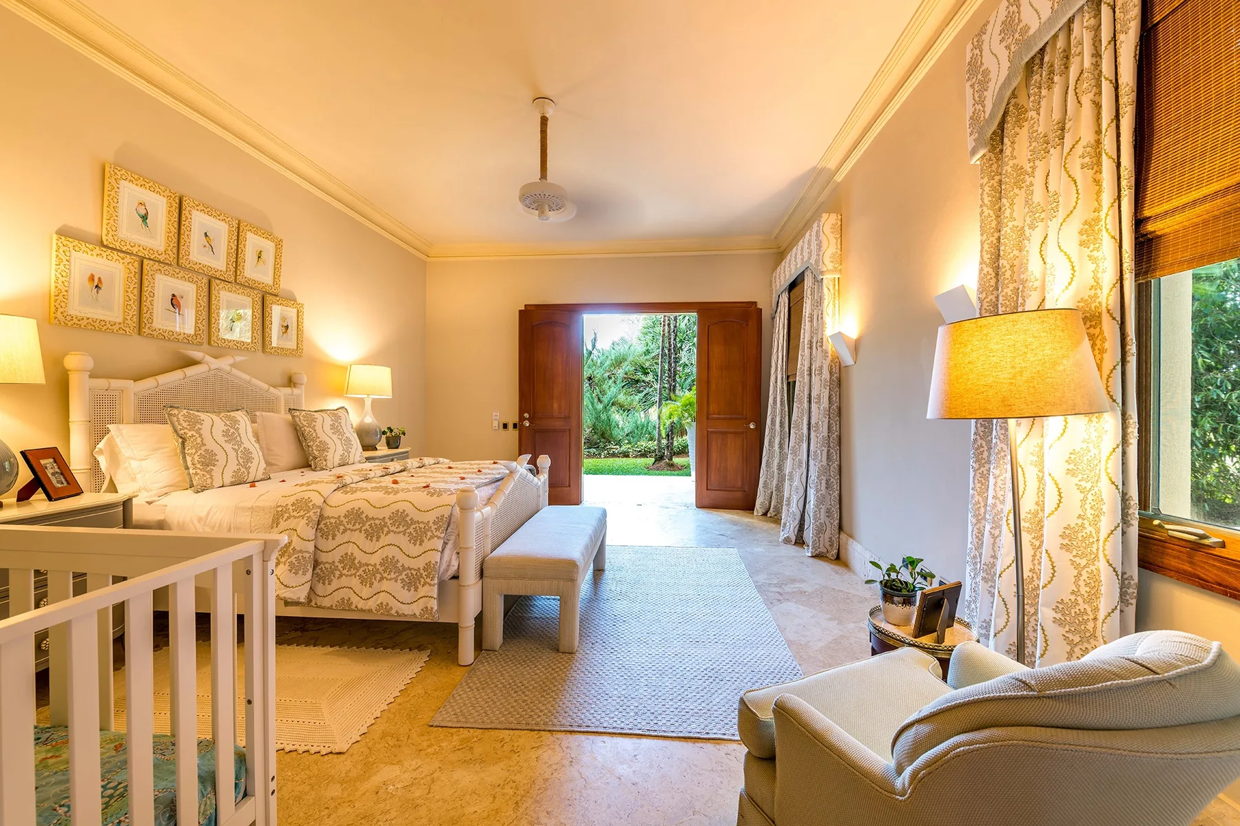 A bedroom with a large bed and open doors overlooking a garden.