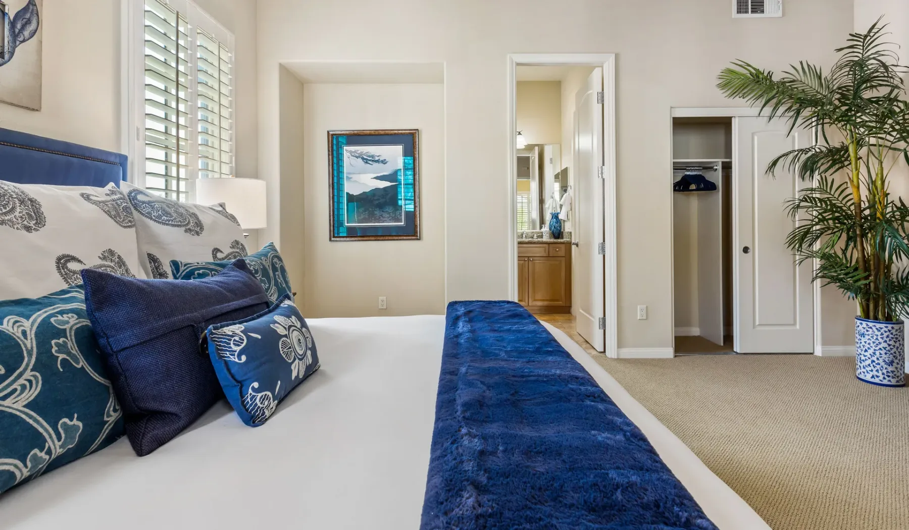 Un dormitorio con una cama vestida con ropa de cama blanca y azul.