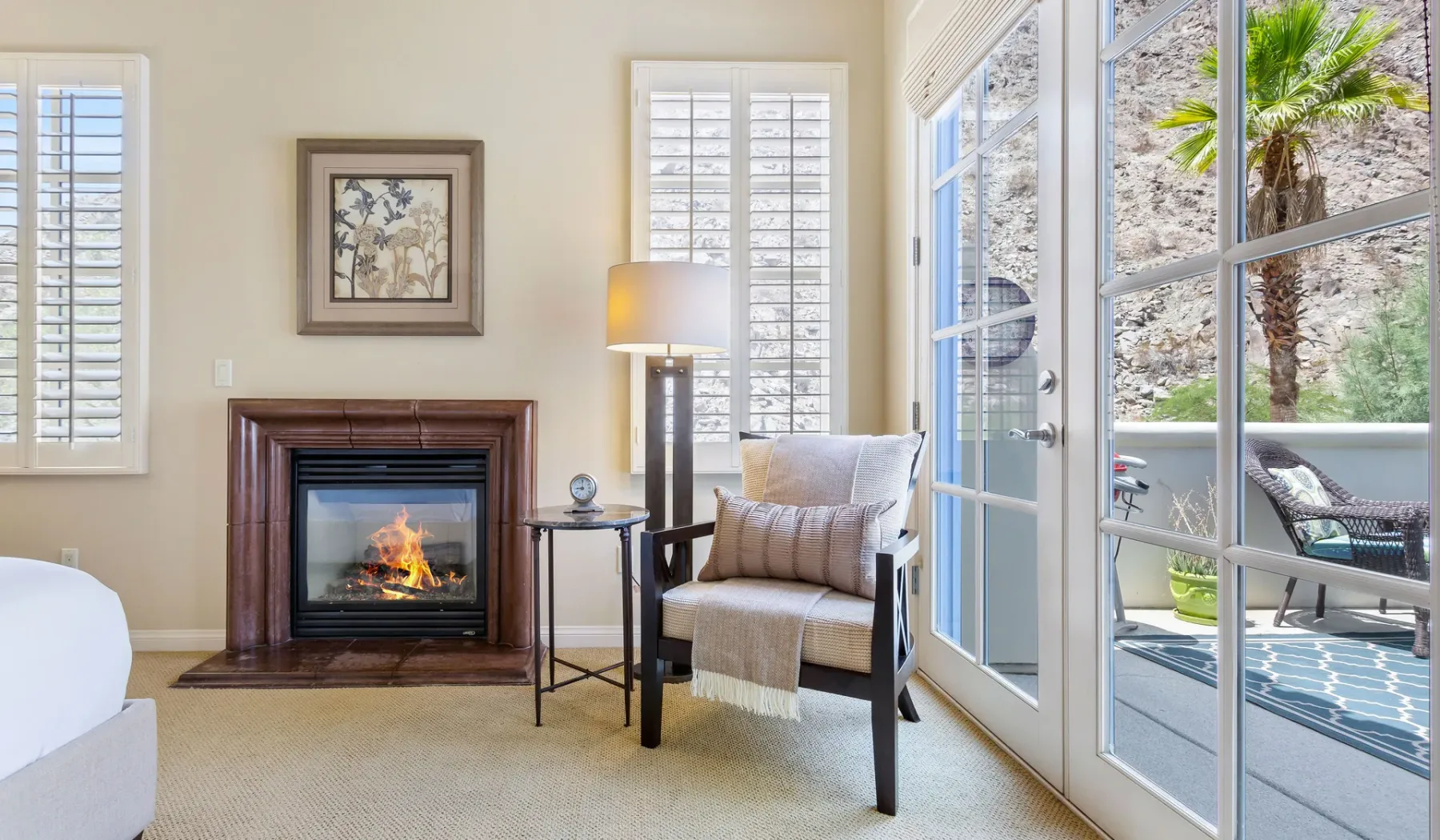 Una sala de estar con chimenea, un sillón y puertas de vidrio que dan a un patio.