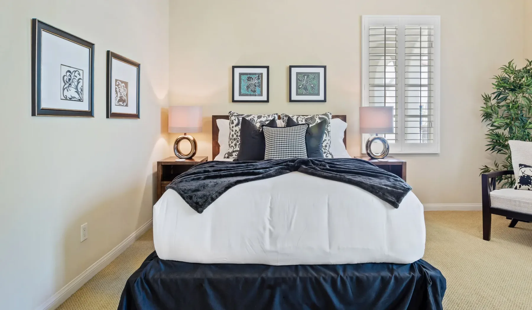 Dormitorio con una cama bien arreglada, cuadros enmarcados y una ventana.