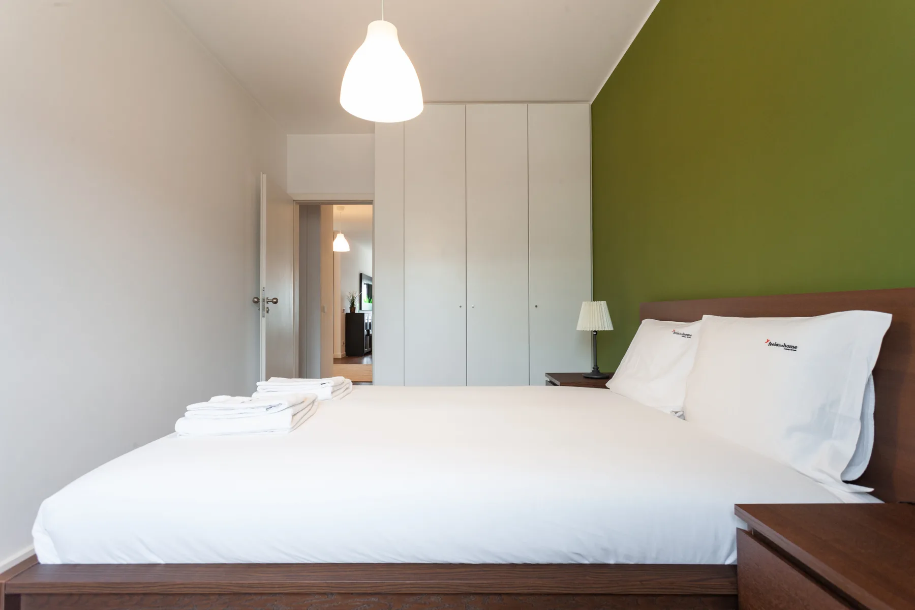 A bedroom with a neatly made bed and built-in wardrobes.