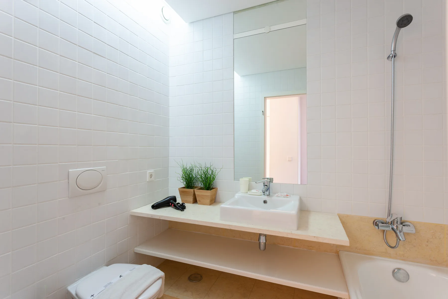 A tiled bathroom with a sink, mirror, and shower.