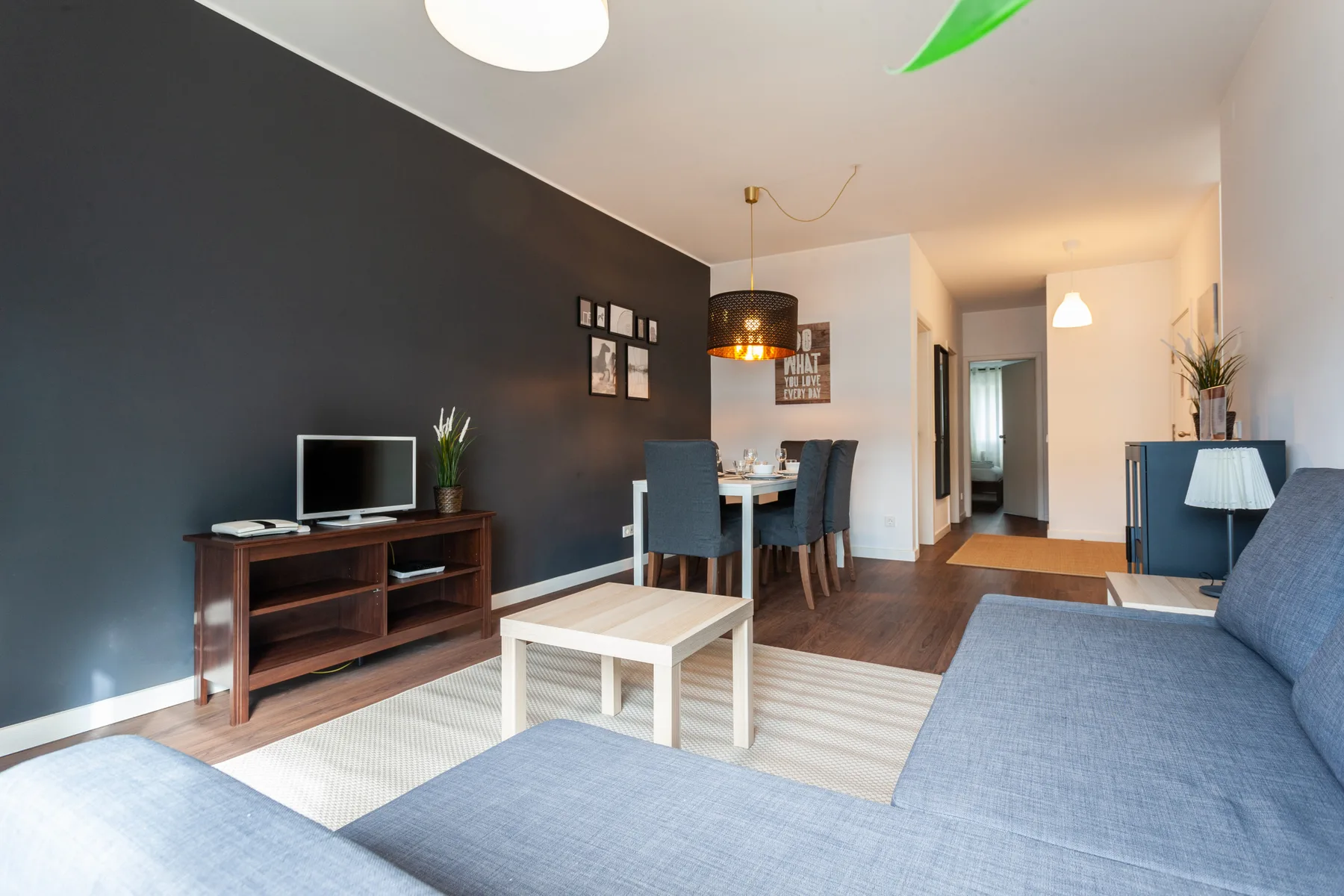 A living and dining area with blue seating, a television, and a dining table.